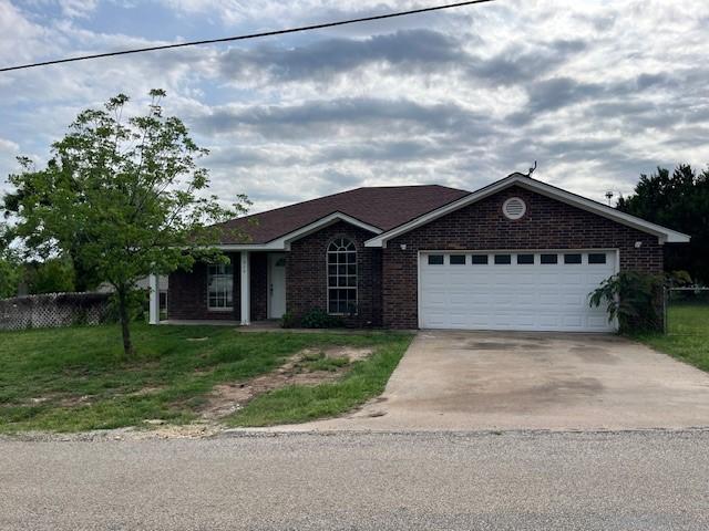 610 N Pecan St, Hico, TX 76457 - ranch-style home with a front lawn, a garage, driveway, brick siding, and fence