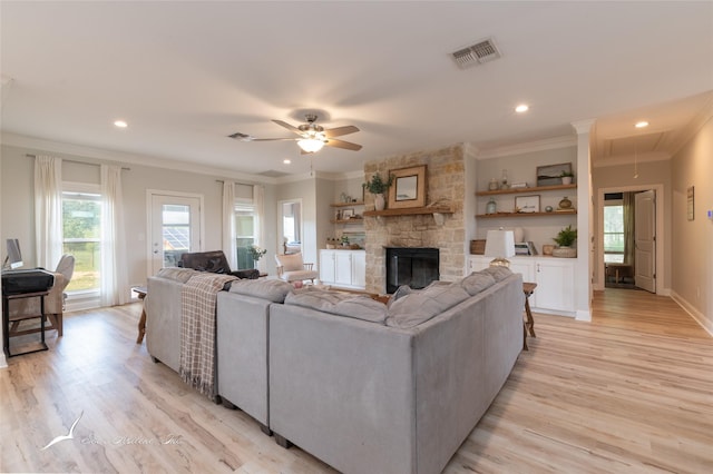 living room featuring attic access, light wood-style floors, ceiling fan, crown molding, and visible vents