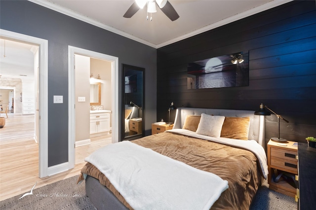 bedroom with connected bathroom, light wood-type flooring, a ceiling fan, baseboards, and ornamental molding
