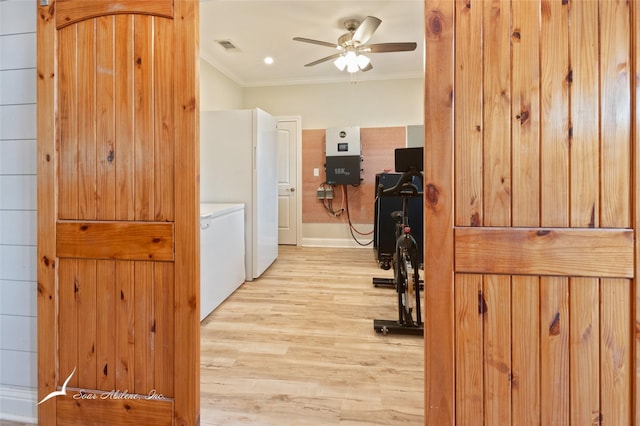 hall with visible vents, light wood finished floors, crown molding, and washing machine and dryer