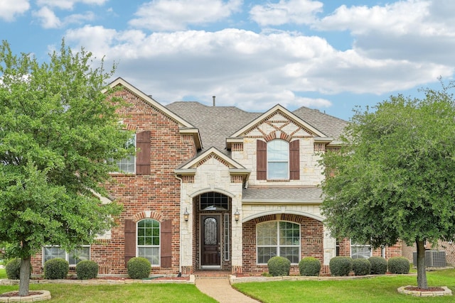 traditional home featuring brick siding, a shingled roof, and a front yard