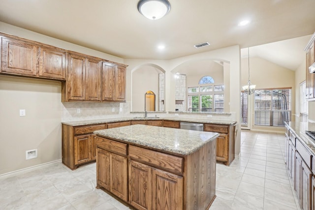 kitchen with visible vents, backsplash, brown cabinetry, and light stone counters