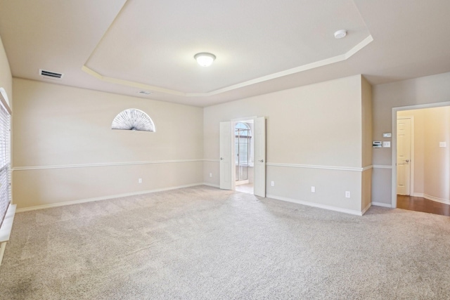 spare room with visible vents, baseboards, a raised ceiling, and carpet floors