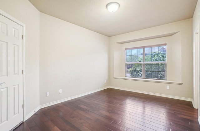 spare room featuring dark wood-style flooring and baseboards