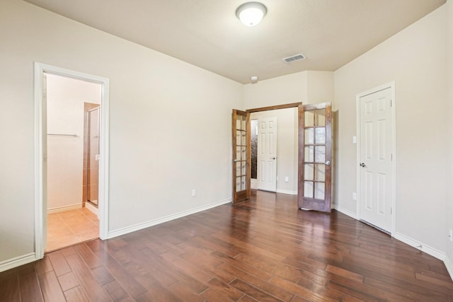 spare room featuring visible vents, baseboards, french doors, and dark wood-type flooring