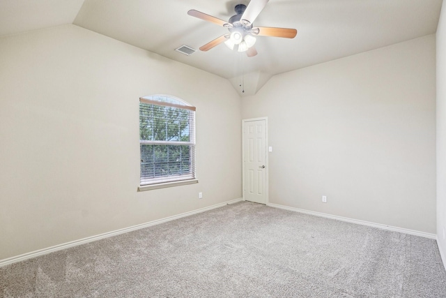 carpeted spare room with lofted ceiling, visible vents, ceiling fan, and baseboards