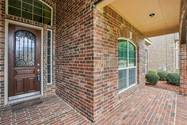 entrance to property with covered porch and brick siding