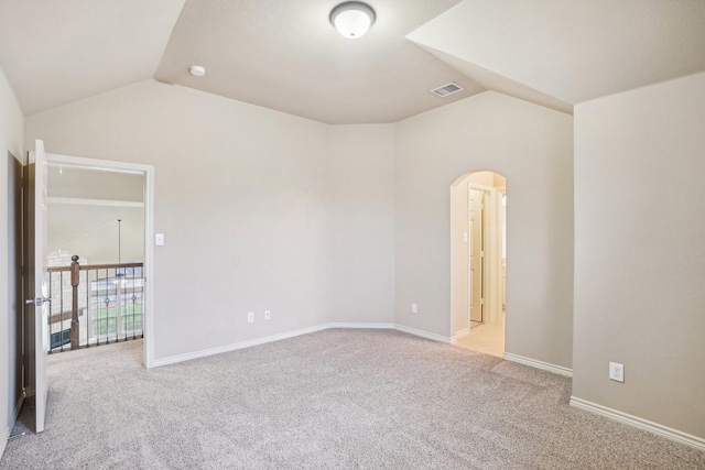 carpeted spare room featuring arched walkways, visible vents, lofted ceiling, and baseboards