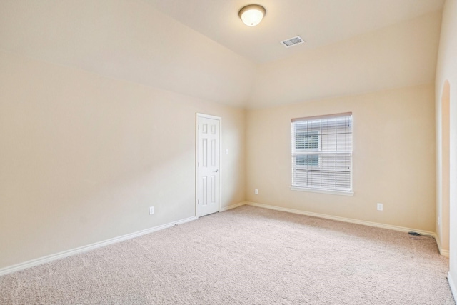 empty room with lofted ceiling, visible vents, baseboards, and light carpet