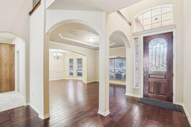 entrance foyer with dark wood-style flooring, visible vents, baseboards, and arched walkways