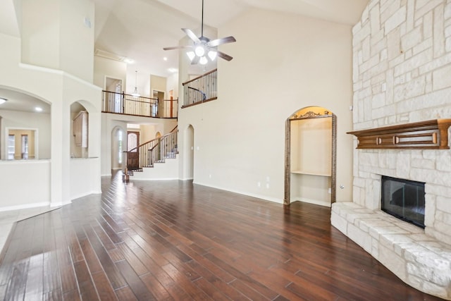 unfurnished living room featuring a fireplace, wood finished floors, ceiling fan, and high vaulted ceiling