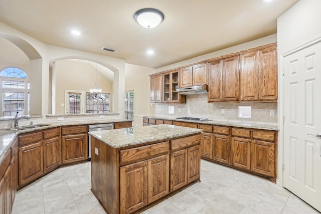 kitchen featuring visible vents, brown cabinets, under cabinet range hood, and a sink
