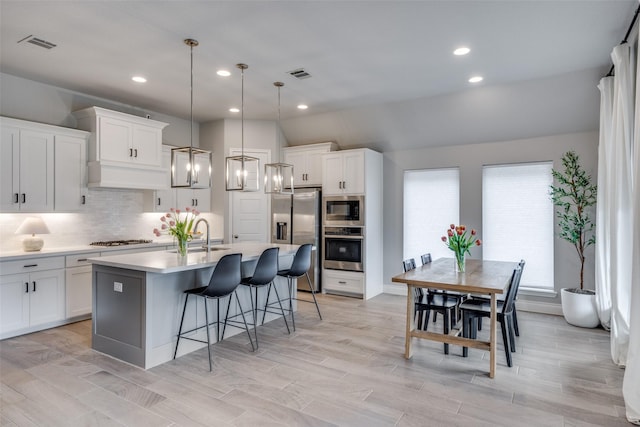 kitchen featuring a kitchen breakfast bar, decorative backsplash, visible vents, stainless steel appliances, and light countertops
