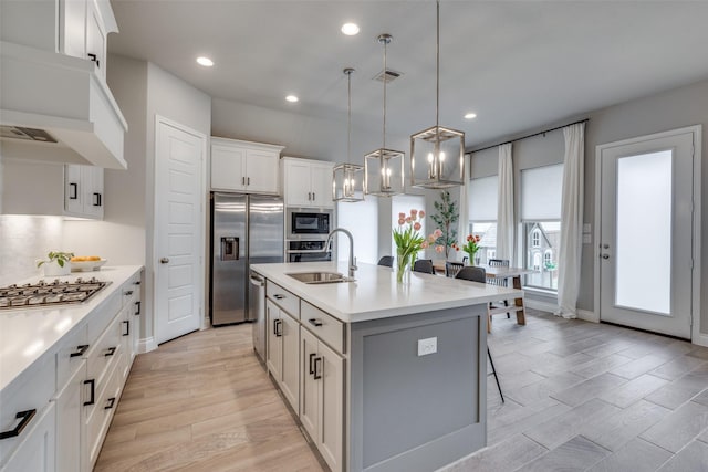 kitchen featuring stainless steel appliances, light wood-style floors, light countertops, and a sink