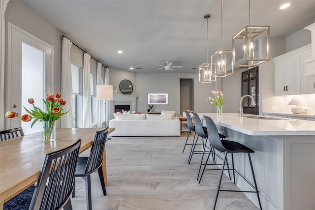 dining space with a fireplace, recessed lighting, and ceiling fan with notable chandelier