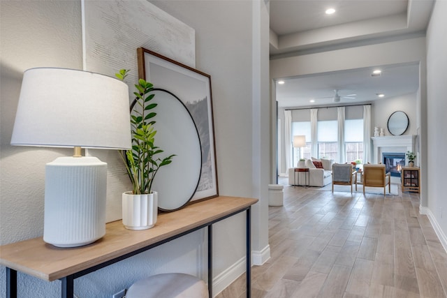 interior space with recessed lighting, light wood-style floors, ceiling fan, a glass covered fireplace, and baseboards