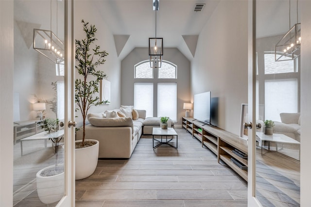 living room with visible vents, french doors, a chandelier, vaulted ceiling, and wood finished floors