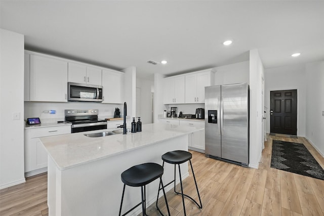 849 Breakwater Dr, Princeton, TX 75407 - kitchen with light wood finished floors, a sink, stainless steel appliances, a breakfast bar area, and white cabinetry