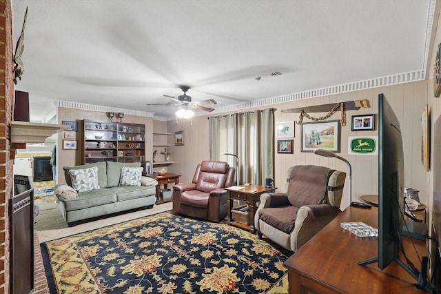 living area with a ceiling fan, visible vents, and a glass covered fireplace