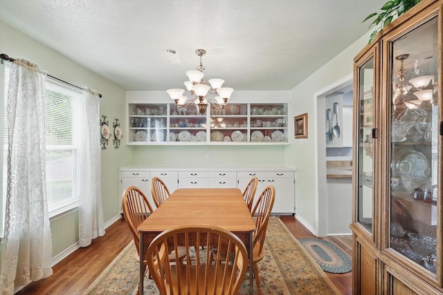 dining space featuring baseboards, wood finished floors, and a notable chandelier