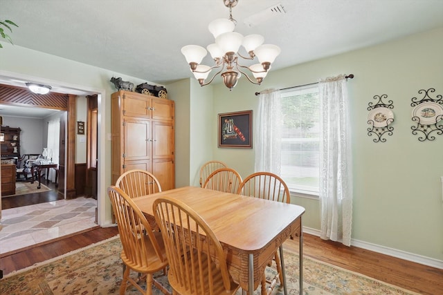 dining space featuring baseboards, visible vents, an inviting chandelier, and light wood-style floors