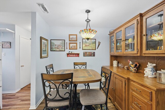dining area featuring visible vents, wood finished floors, and baseboards