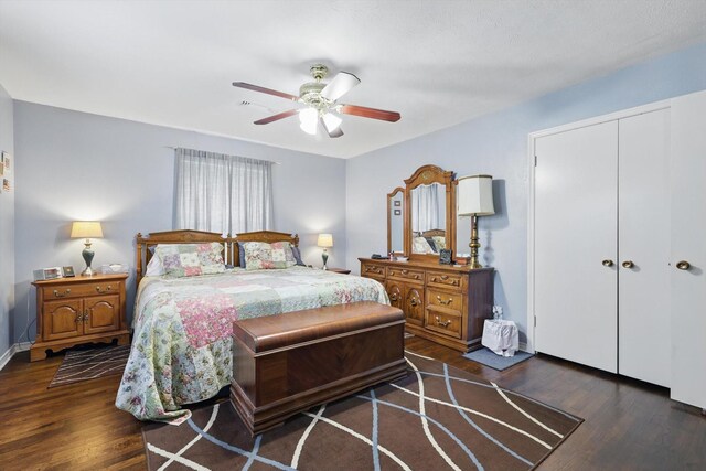 bedroom with dark wood finished floors, baseboards, a ceiling fan, and a closet