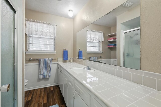 full bath featuring a shower stall, vanity, toilet, a textured wall, and wood finished floors