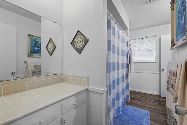 full bathroom featuring wood finished floors, vanity, a shower with curtain, and backsplash