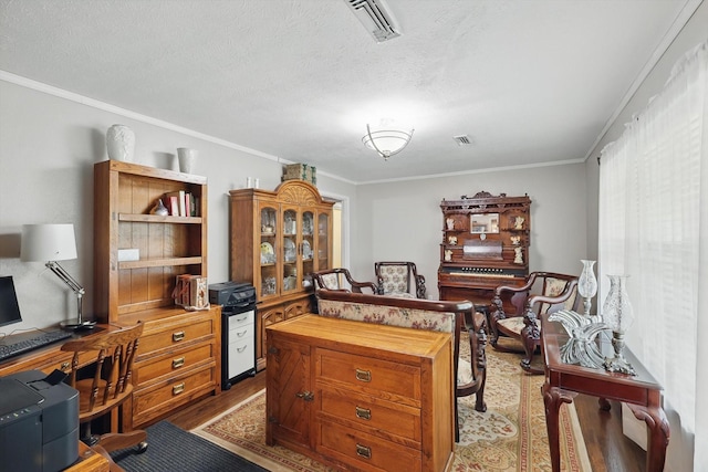 office with a textured ceiling, wood finished floors, crown molding, and visible vents