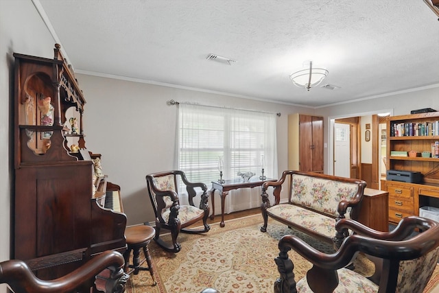 living area with visible vents, a textured ceiling, wood finished floors, and ornamental molding