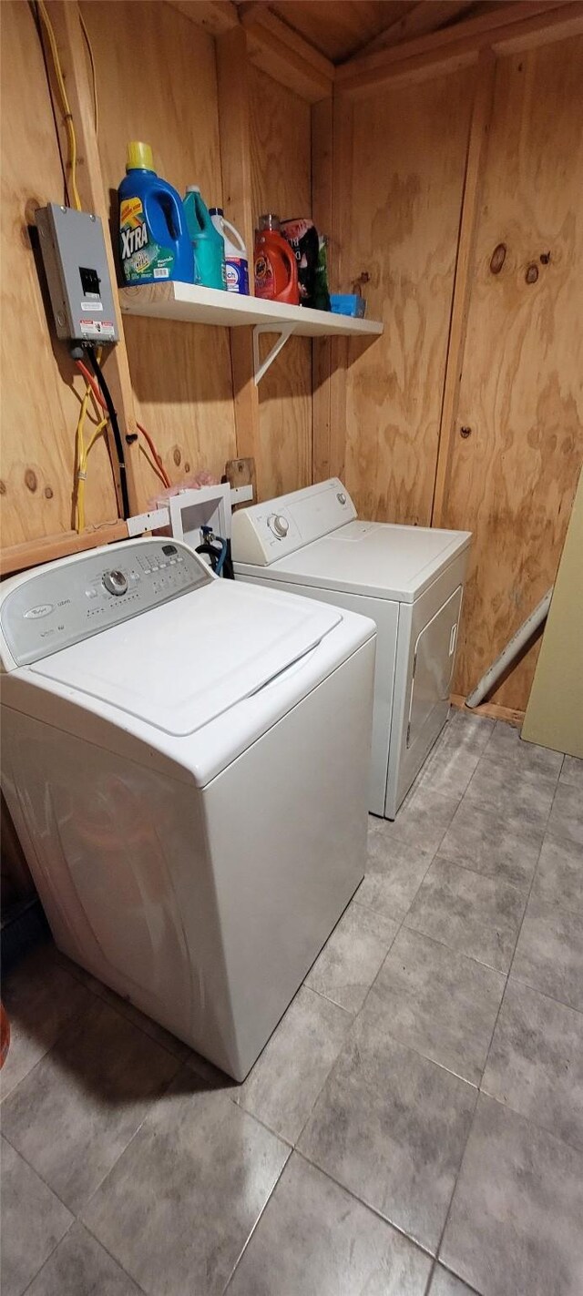 washroom featuring wooden walls, washing machine and clothes dryer, and laundry area