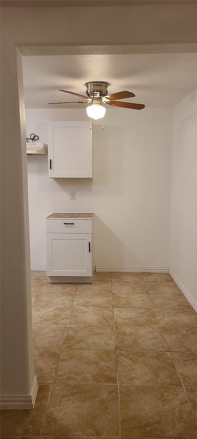 unfurnished room featuring baseboards, light tile patterned floors, and a ceiling fan