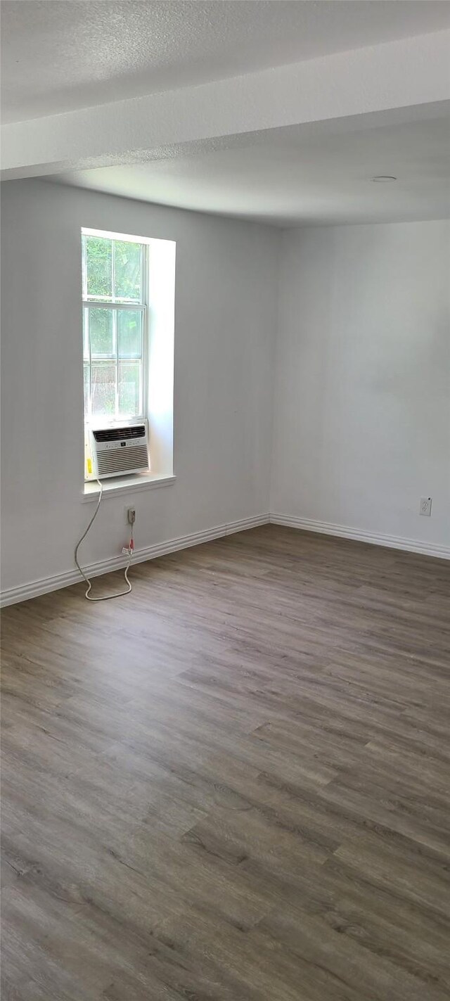 spare room with dark wood-style flooring and baseboards