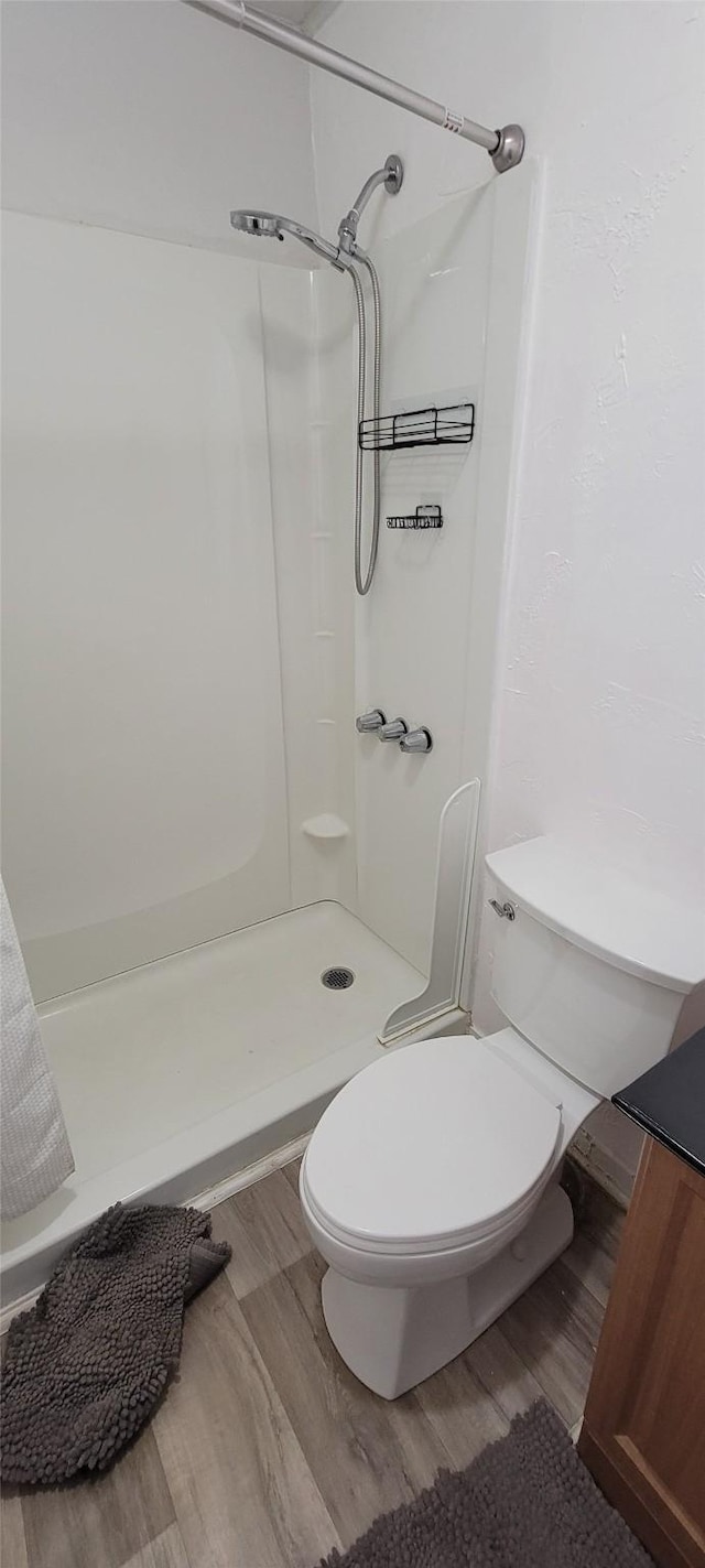 full bath featuring wood finished floors, toilet, and a shower stall