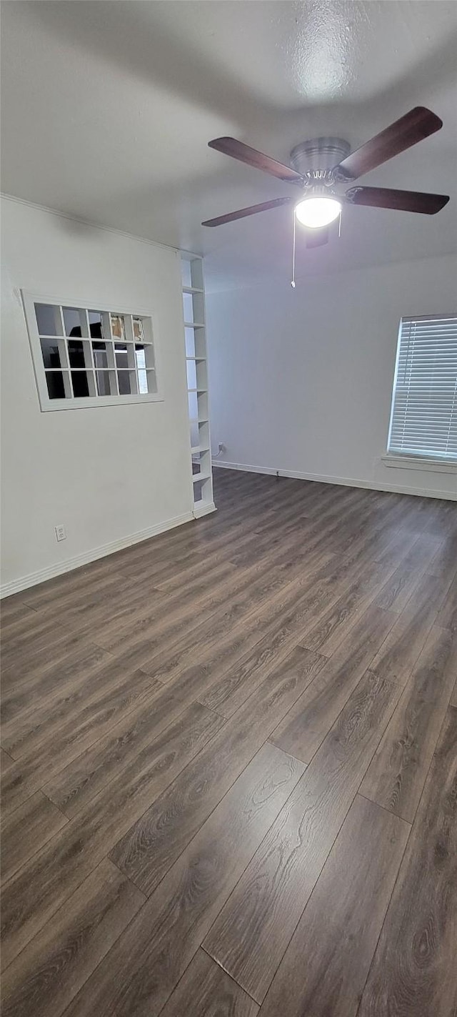 empty room with a ceiling fan, dark wood-style flooring, and baseboards