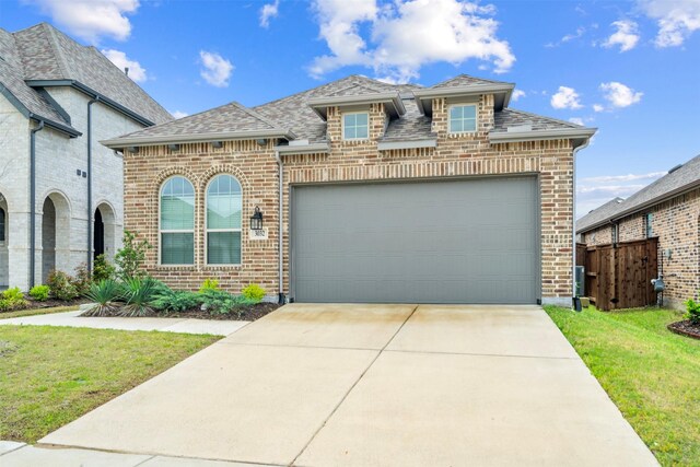french provincial home featuring a front yard, roof with shingles, fence, and brick siding