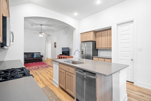 kitchen with light brown cabinetry, arched walkways, appliances with stainless steel finishes, and a sink