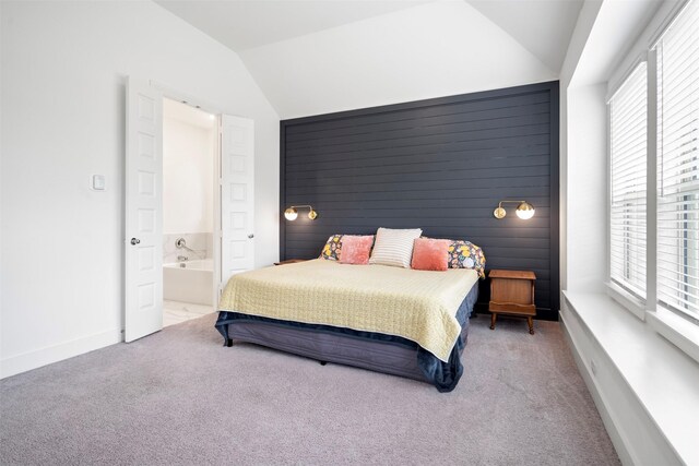 carpeted bedroom featuring ensuite bathroom, vaulted ceiling, and baseboards