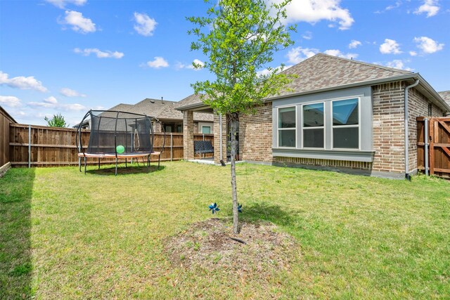 view of yard featuring a trampoline and a fenced backyard