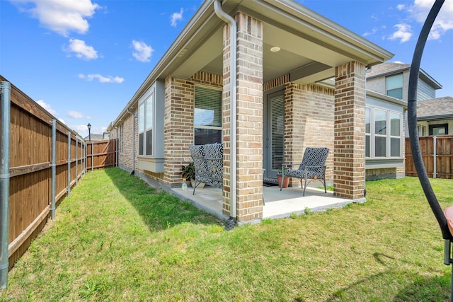 view of home's exterior with a patio, brick siding, a fenced backyard, and a yard
