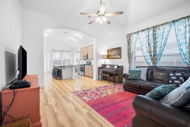 living area with arched walkways, light wood finished floors, visible vents, a ceiling fan, and lofted ceiling