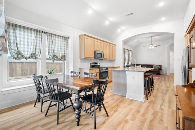 dining space with light wood-style flooring, ceiling fan, visible vents, and arched walkways
