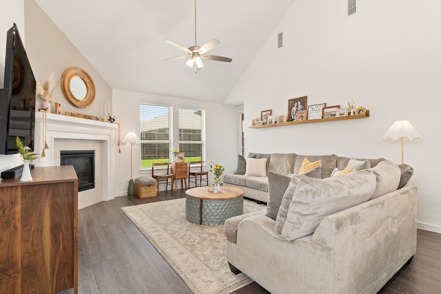 living area featuring a ceiling fan, visible vents, high vaulted ceiling, and dark wood finished floors
