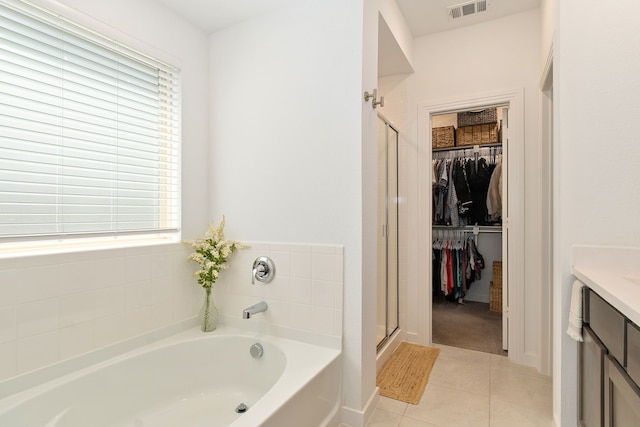 bathroom with a spacious closet, a bath, vanity, visible vents, and a stall shower