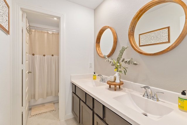 full bath with shower / bath combo with shower curtain, double vanity, a sink, and tile patterned floors