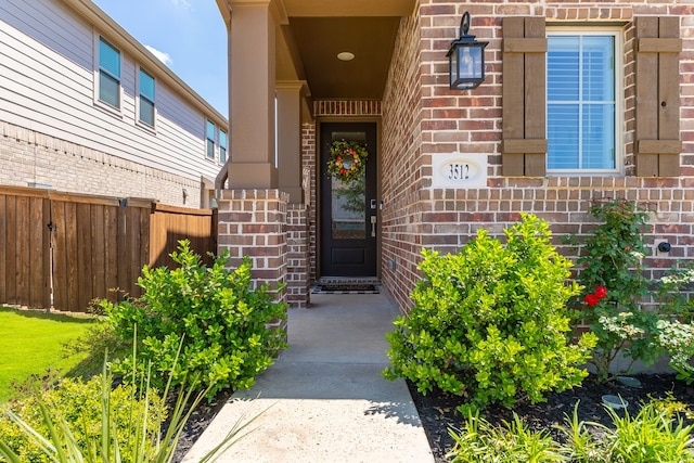 doorway to property with brick siding and fence