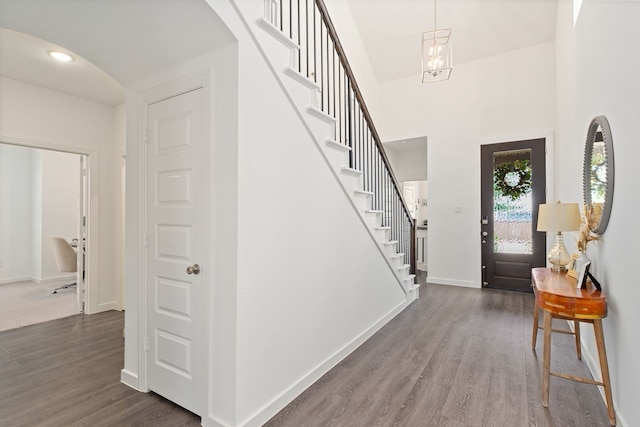 foyer featuring baseboards, arched walkways, stairway, and dark wood finished floors
