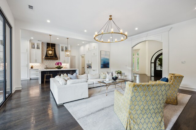 living area featuring recessed lighting, arched walkways, a chandelier, and dark wood-style floors