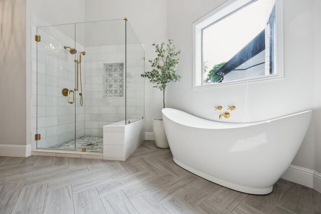 bathroom featuring a freestanding tub, a shower stall, and baseboards